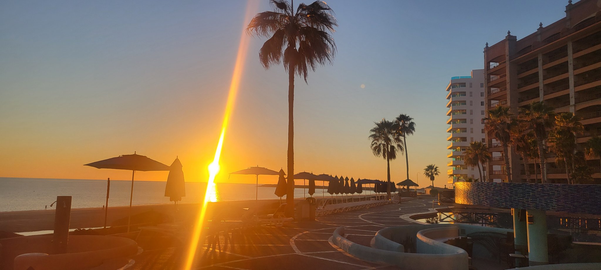 Golden sun setting over the Sea of Cortez beyond the resort pool deck