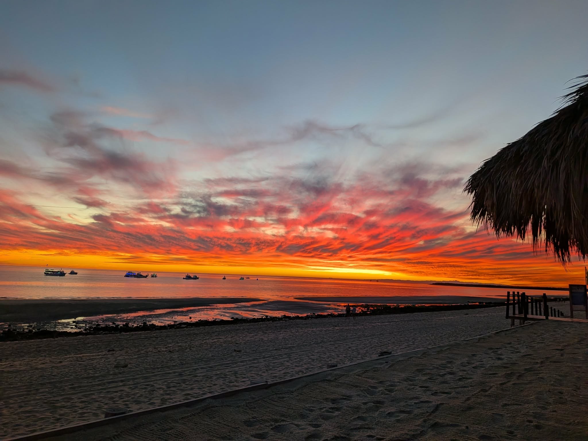 Red and orange sunset clouds stretching over the beach and calm sea